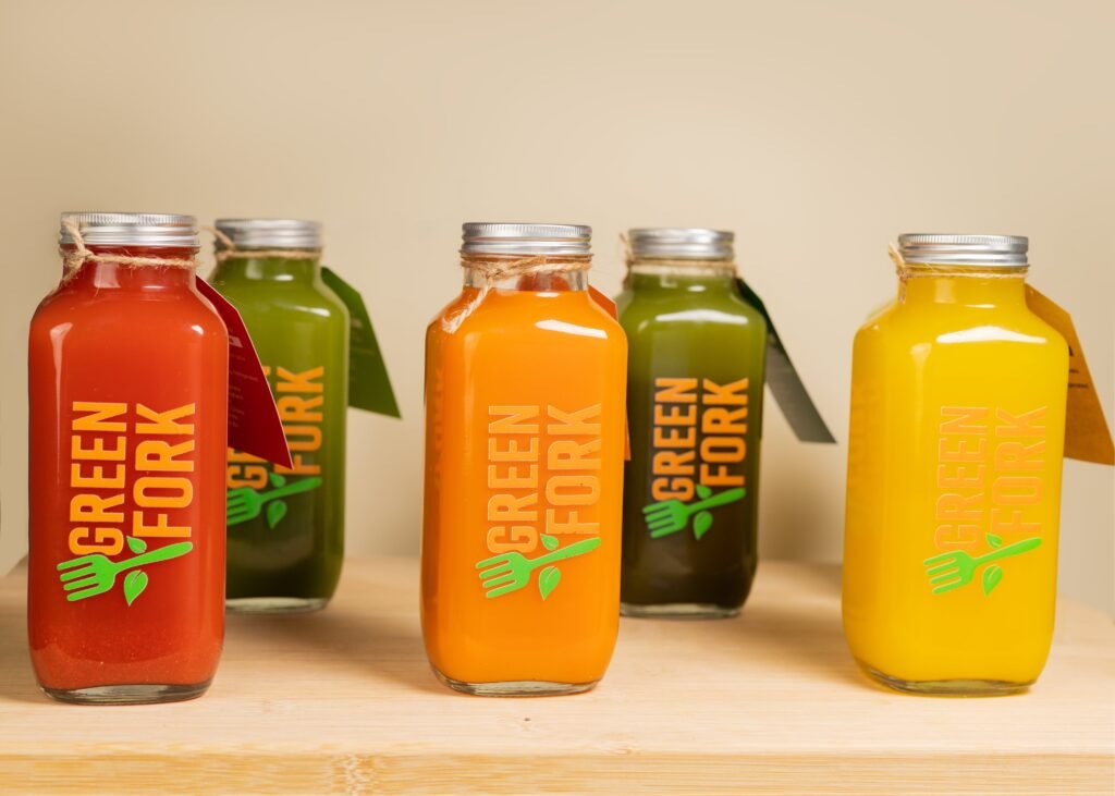 A row of Greenfork juice bottles in red, green and orange