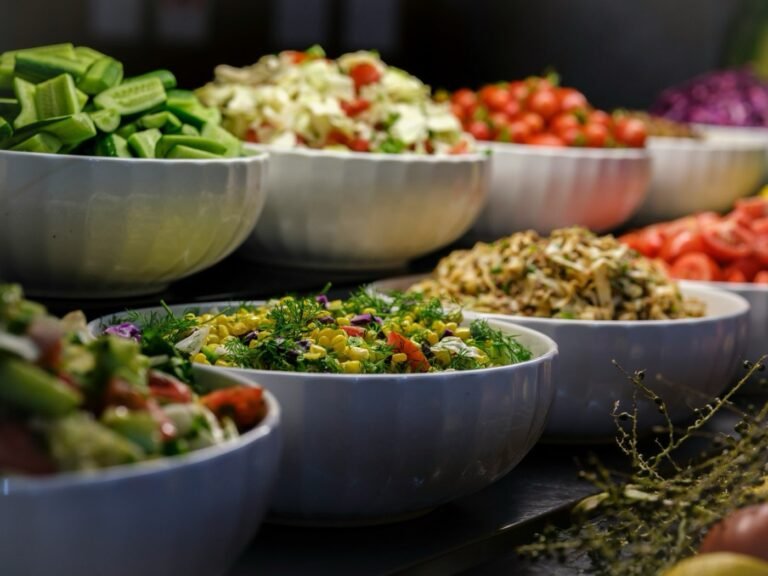 A row of large serving bowls of salad laid out for a group