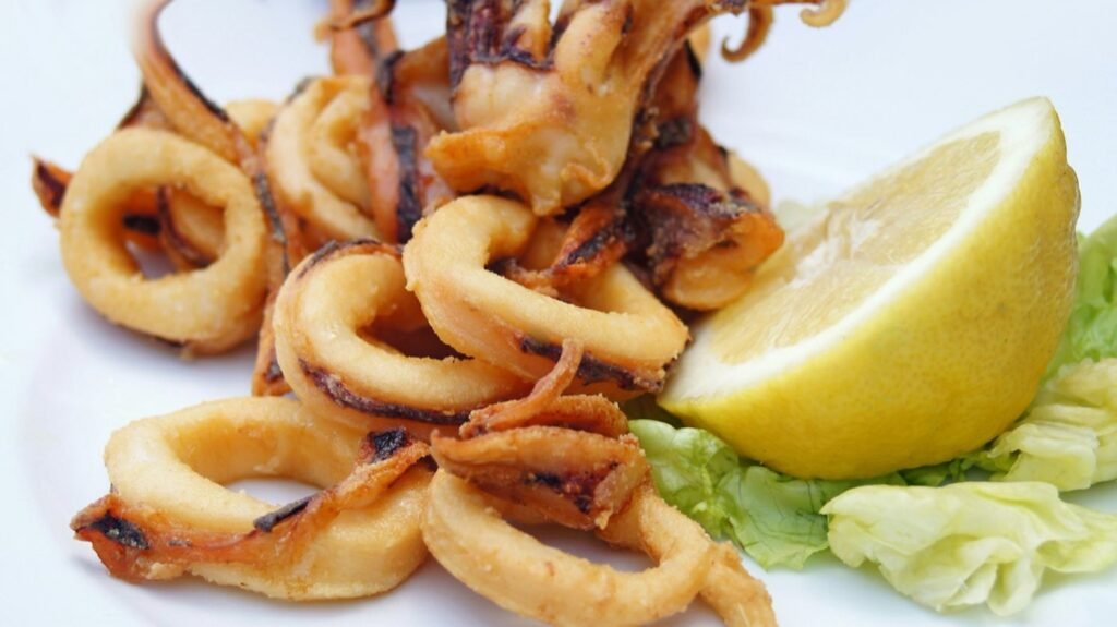 Golden fried calamari rings served with a lemon wedge and salad leaves