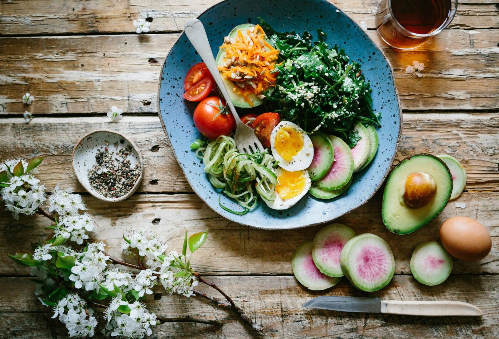 A garden salad bowl of leaves, tomato and avocado on a table