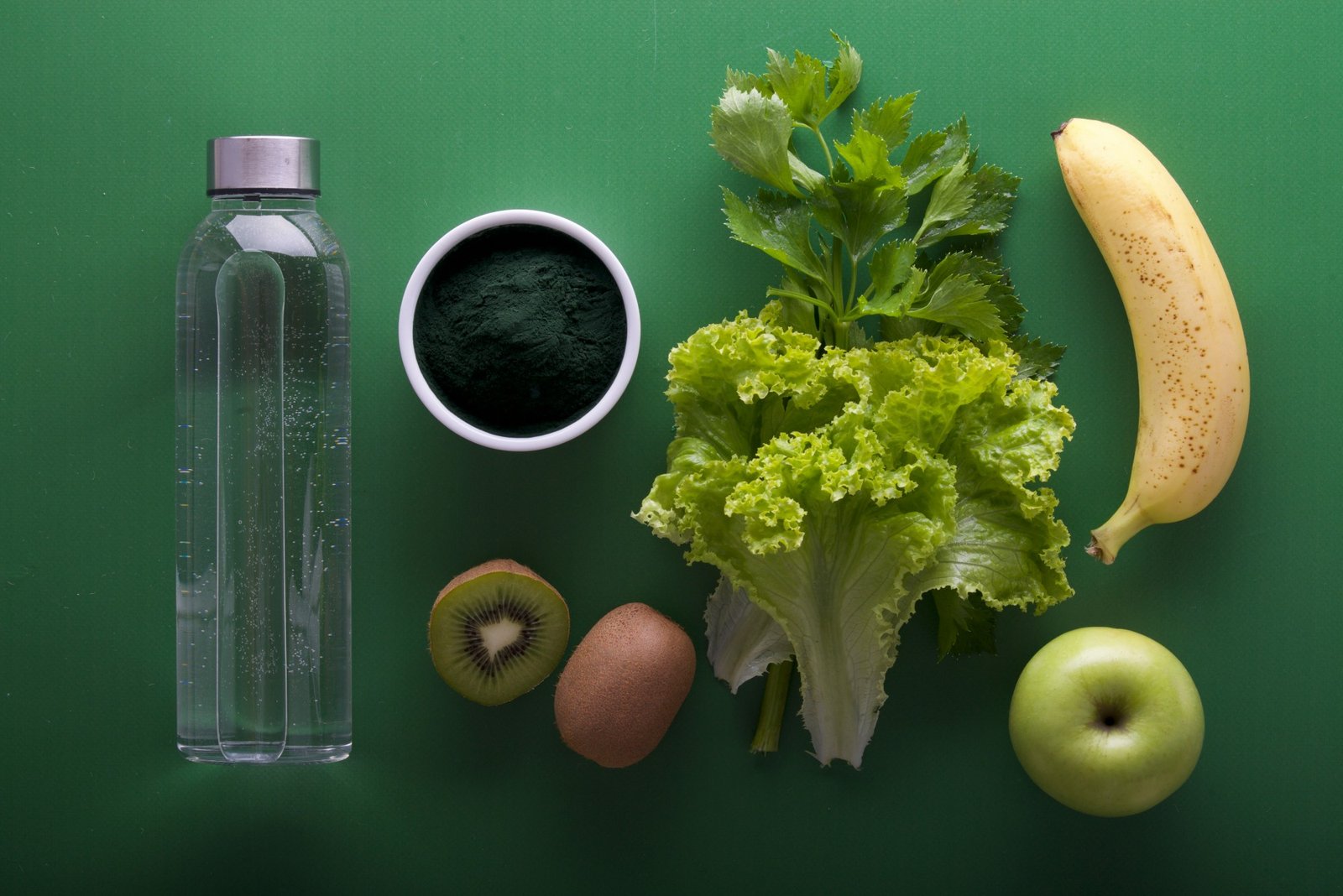 Fresh green vegetables, herbs and fruit laid out on a board