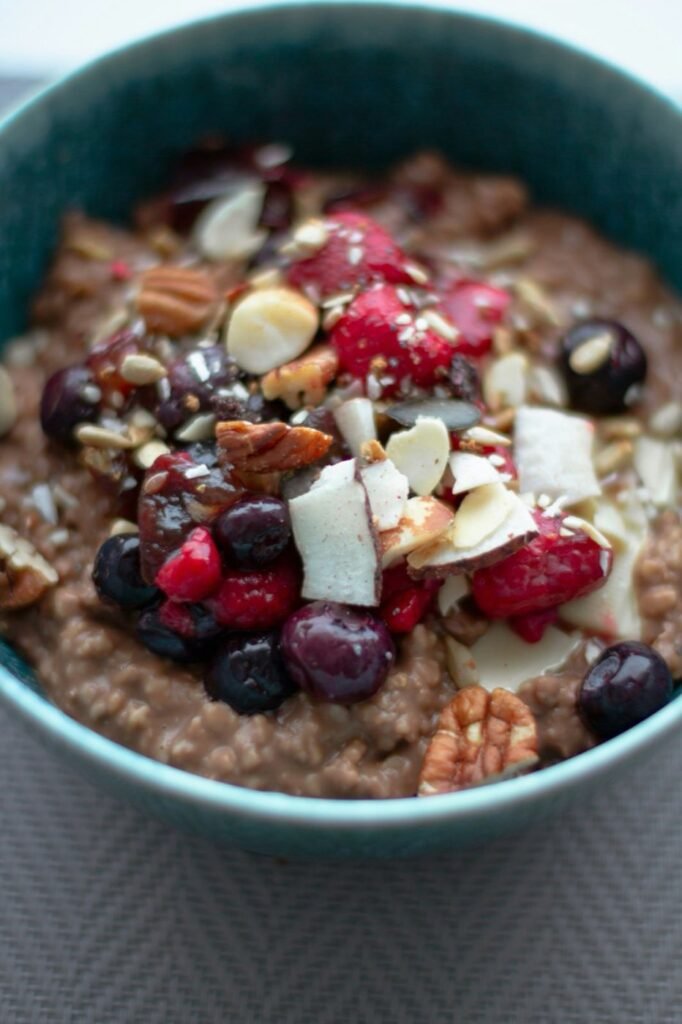 A bowl of chocolate oats topped with berries, coconut flakes and nuts